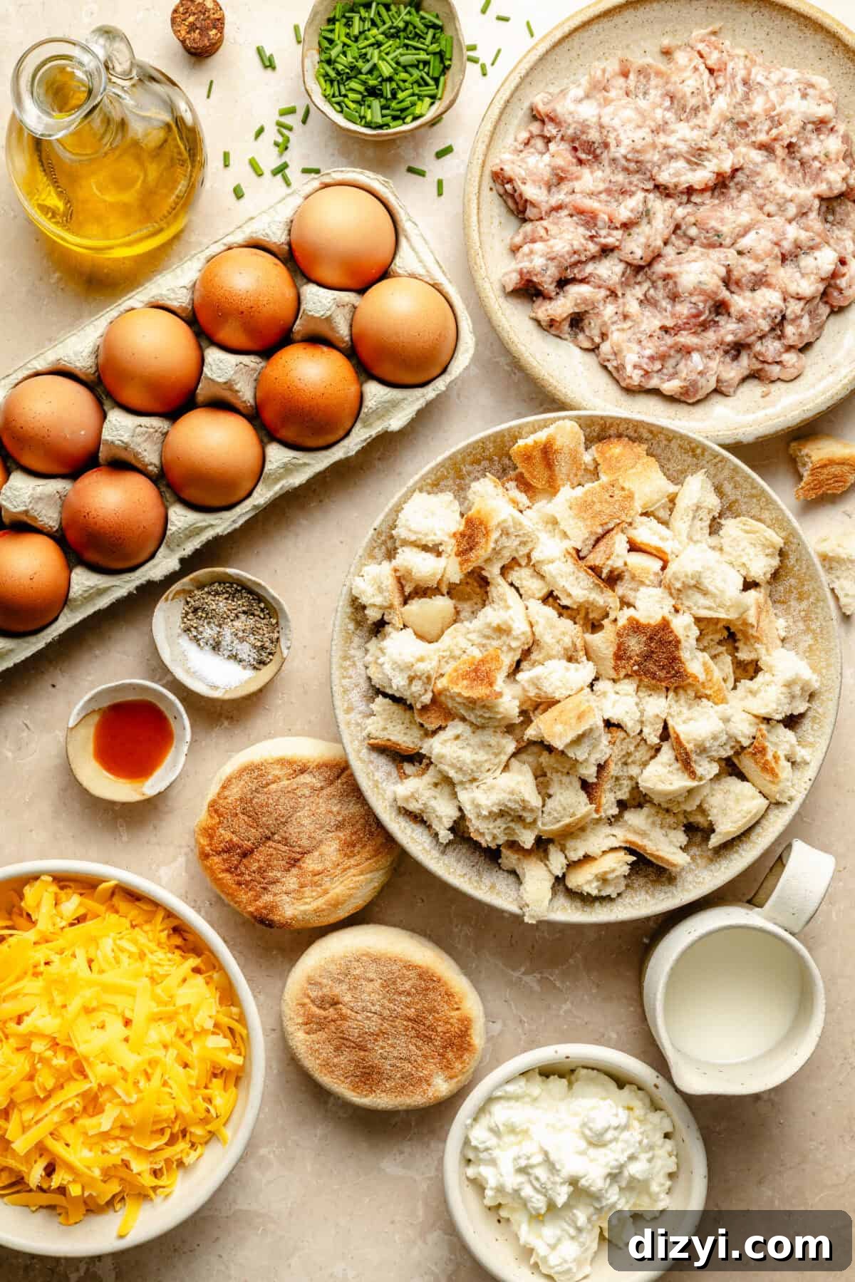a flat lay of ingredients including eggs, torn english muffins, cheese, and ground sausage