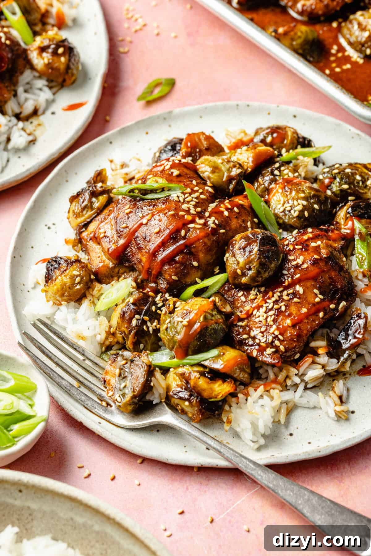 sheet-pan ginger-orange chicken over a bed of white rice on a white plate