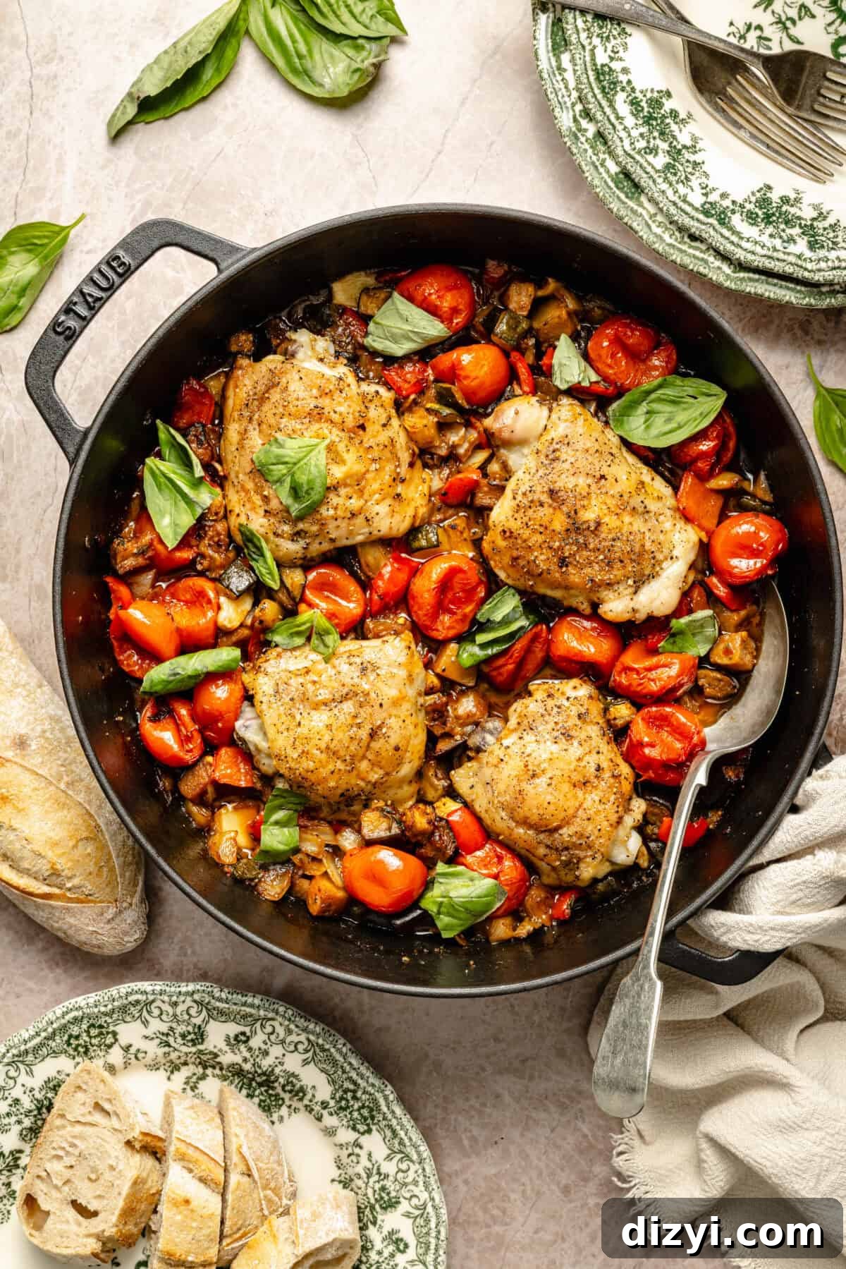 a cast-iron skillet with sautéed vegetables and seared chicken thighs with fresh basil and crusty bread