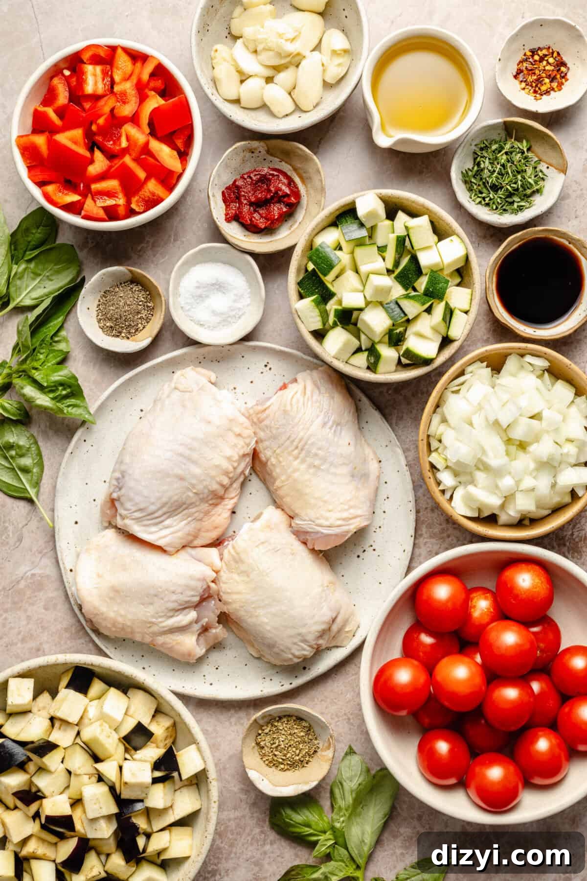 a flat-lay of ingredients to make roasted chicken ratatouille featuring vegetables, oil, and fresh herbs