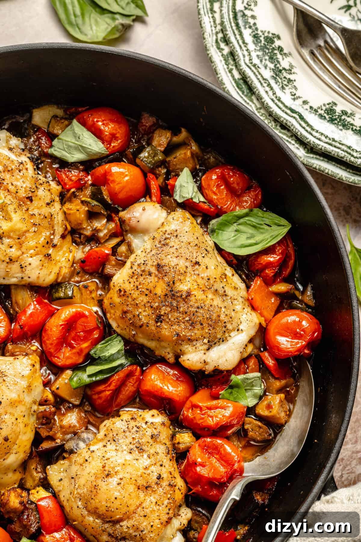 a close-up of roasted chicken thighs and vegetables in a cast-iron braiser