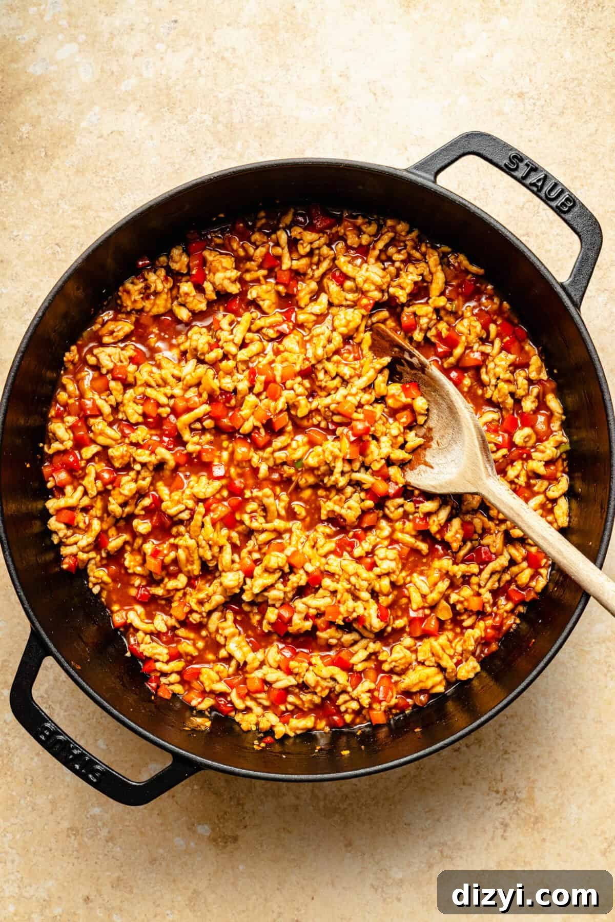 a cast iron skillet with ground chicken, bell peppers, and red pepper flakes