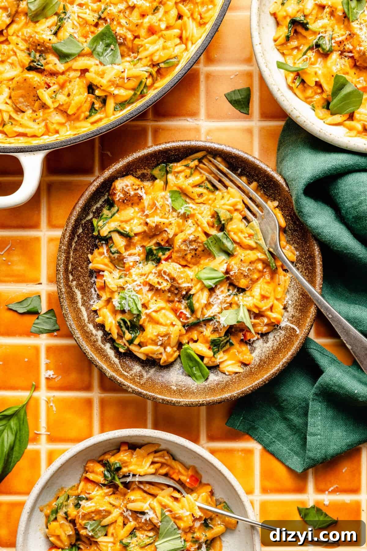 three plates of creamy tomato orzo and sausage garnished with torn fresh basil