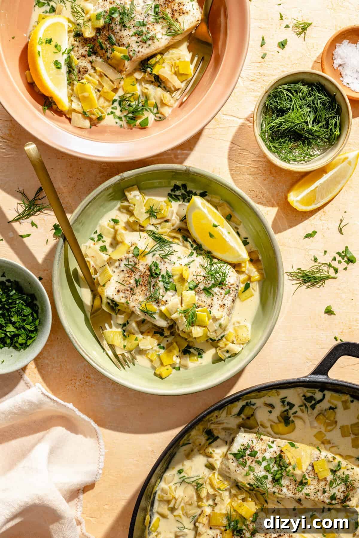 halibut and creamy leek sauce on plates with fresh herbs and lemon wedges