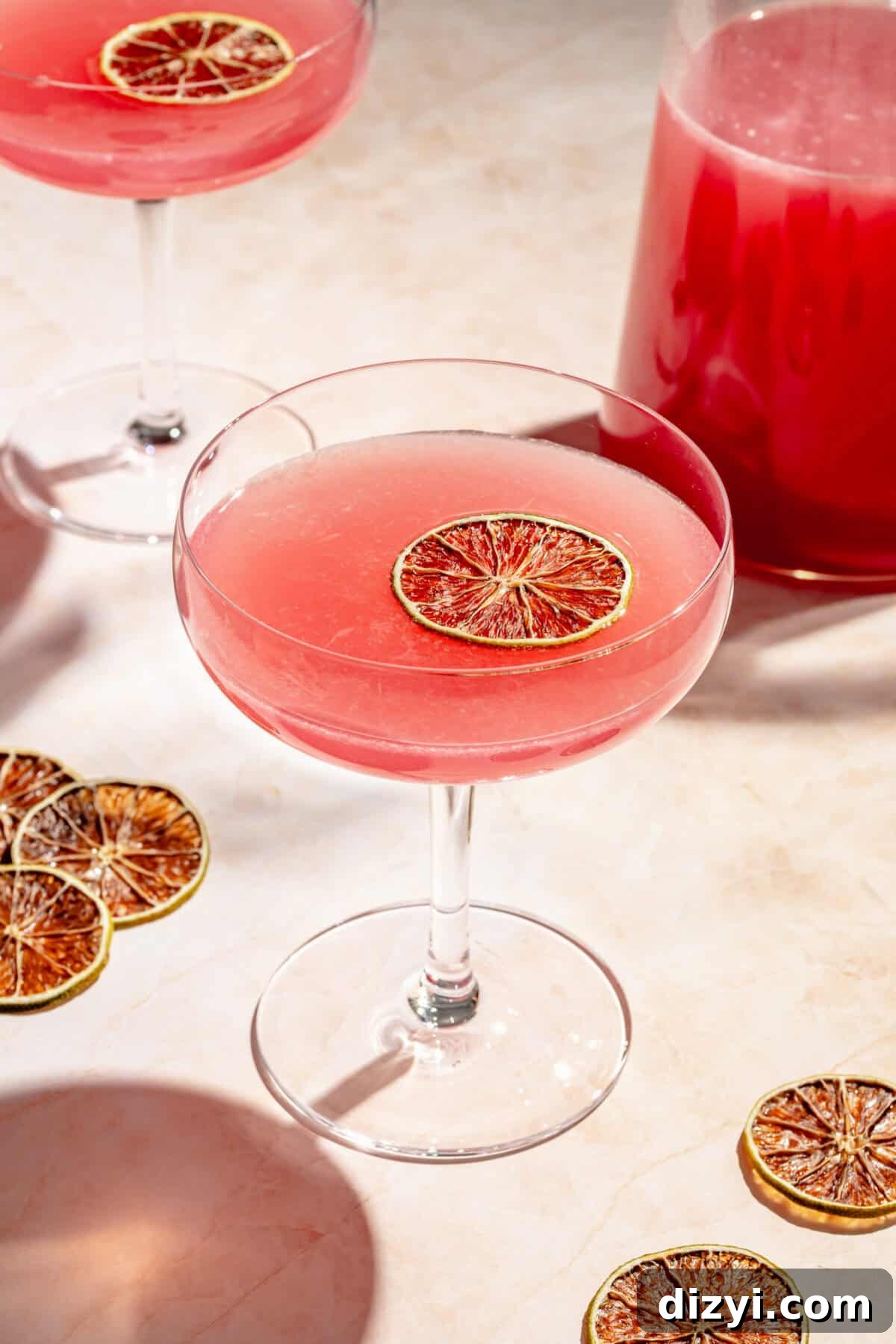 How to Batch Cosmopolitan Cocktails for a Crowd 3 a coupe glass with a cosmopolitan cocktail and dried citrus round