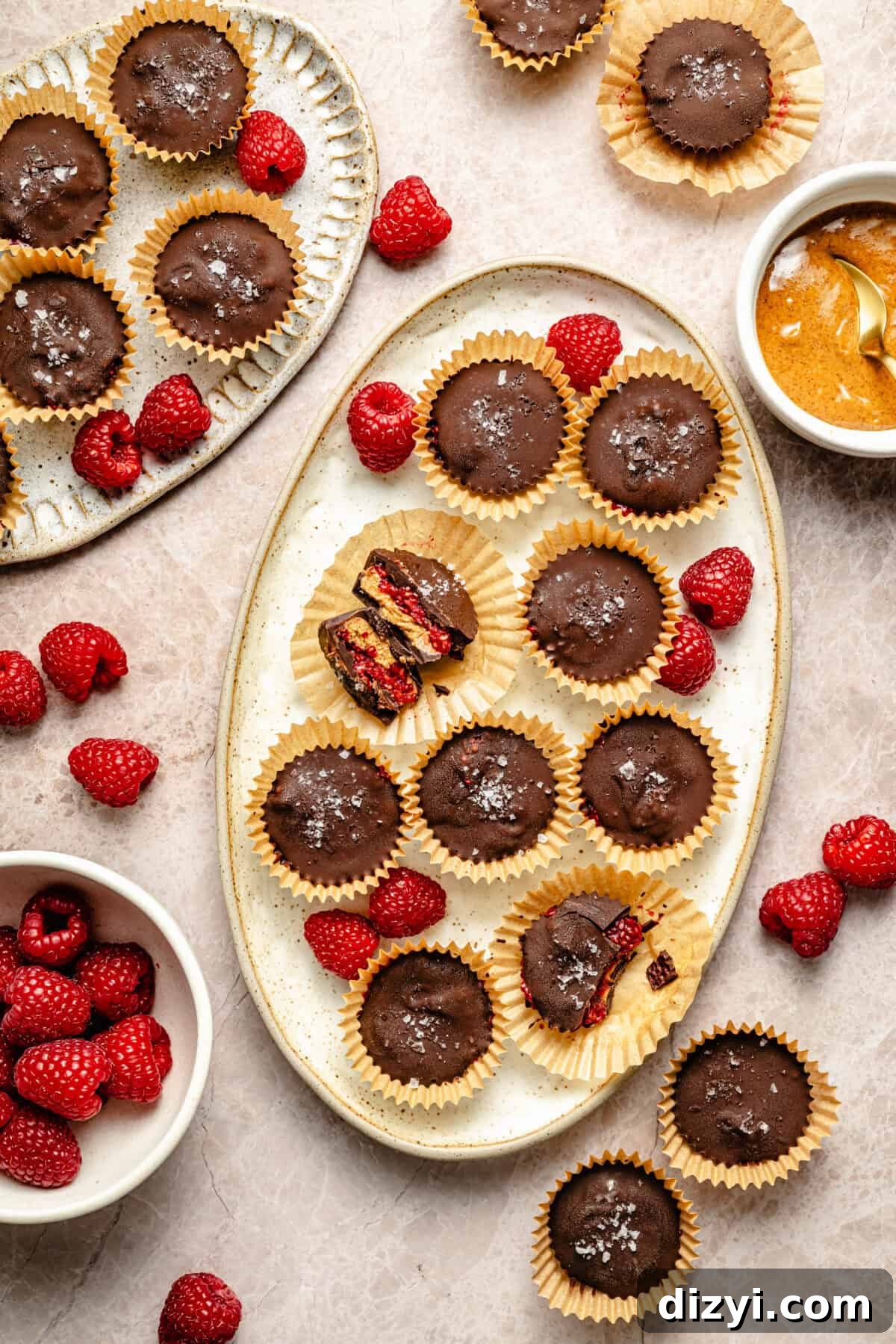two platters with chocolate, raspberry, and almond butter cups with fresh raspberries