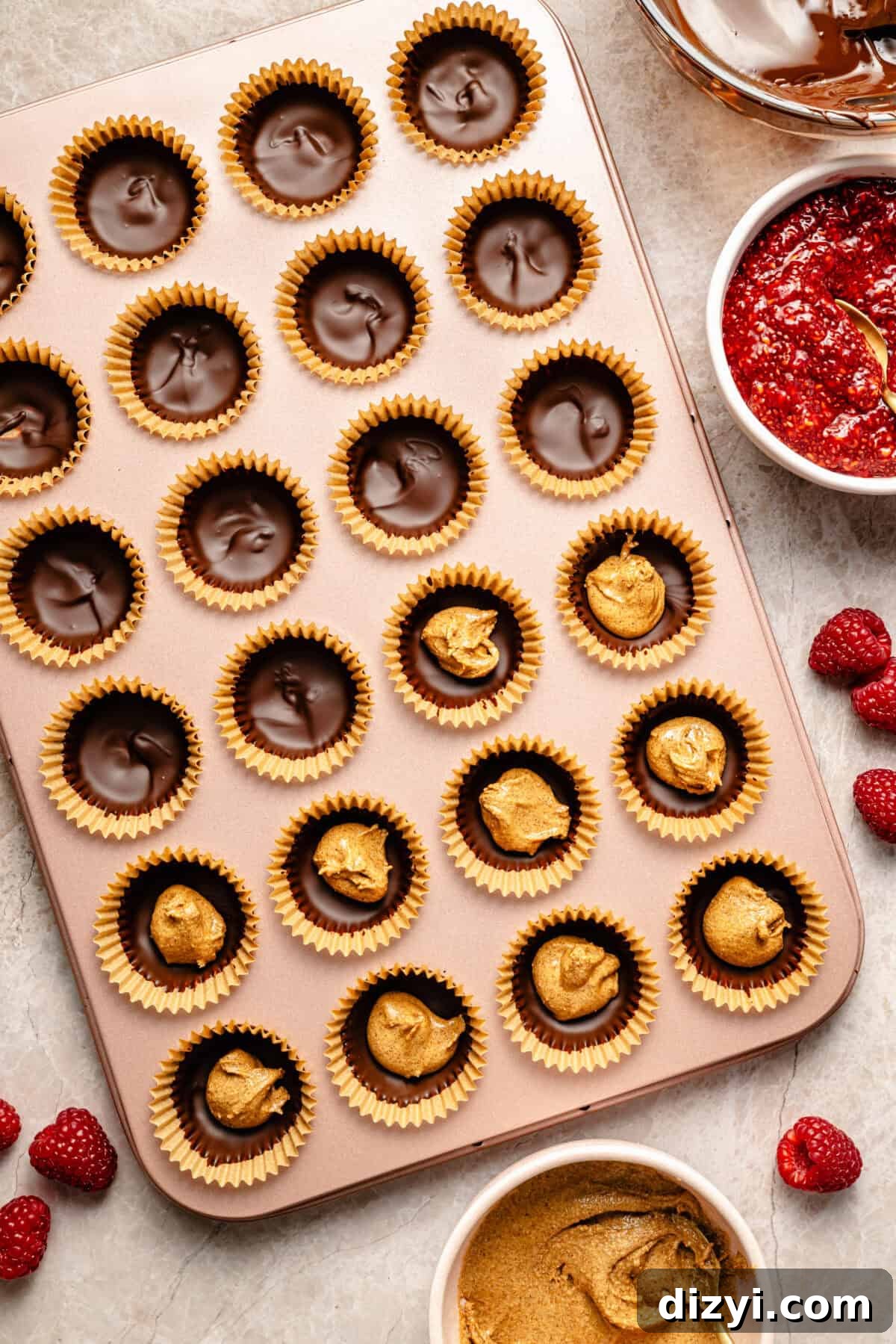 a mini muffin tin with almond butter and chocolate cups in paper liners