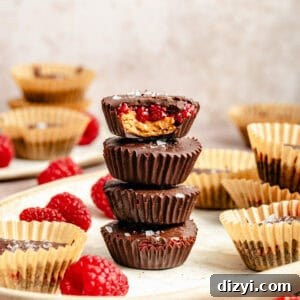 a tall stack of unwrapped and homemade almond butter and raspberry cups with chocolate