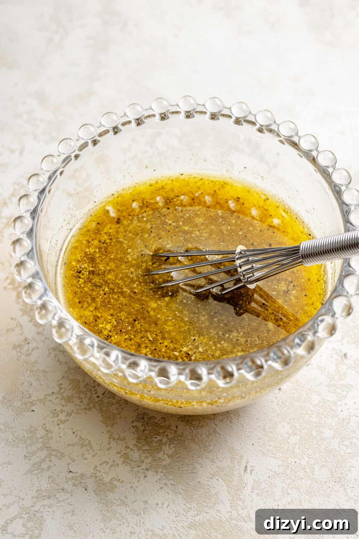 a small glass mixing bowl with salad dressing