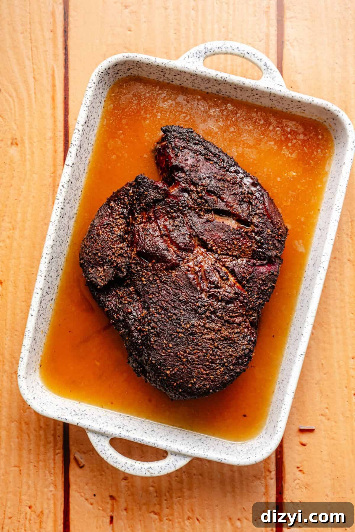 chuck roast in braising liquid in a white baking dish