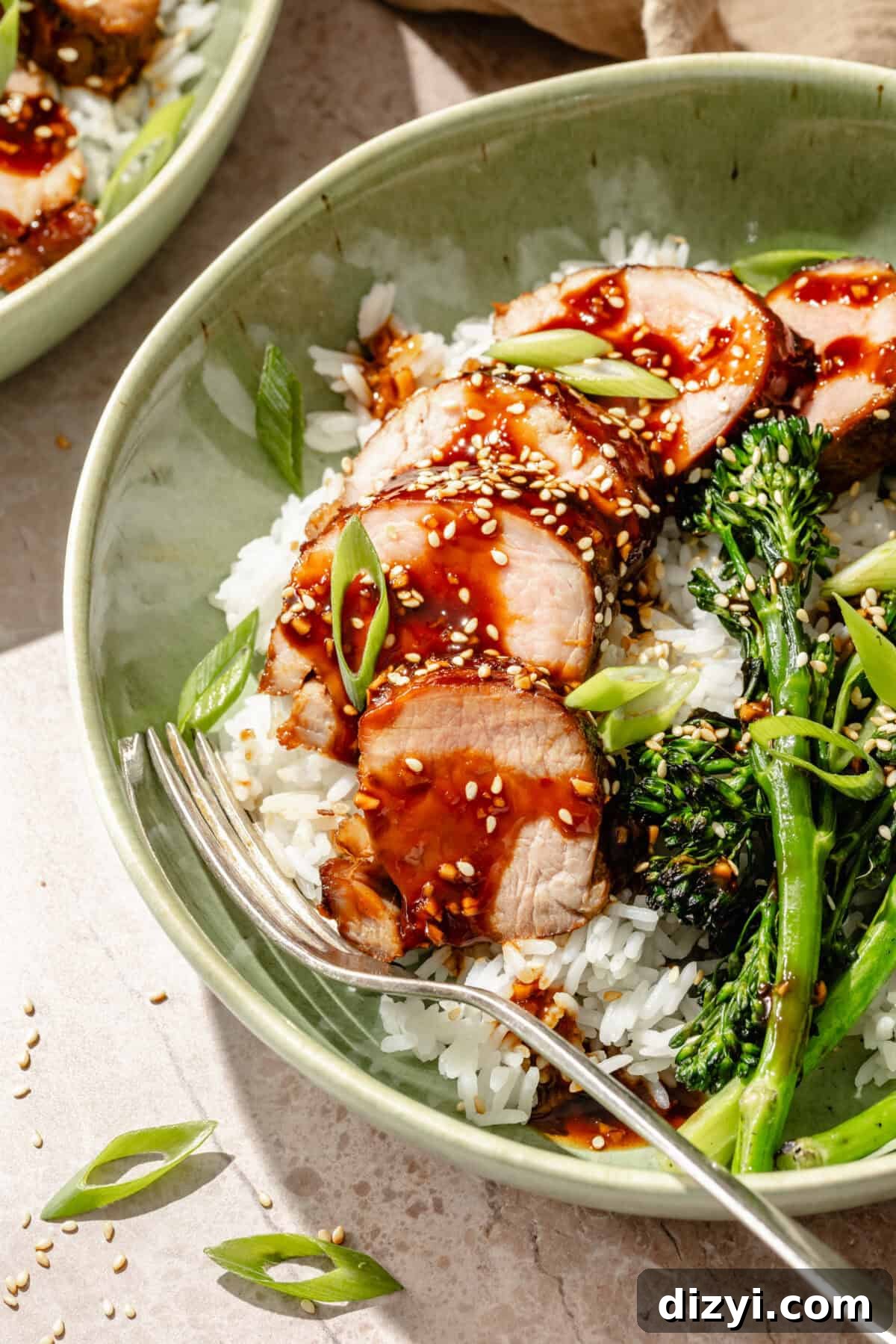 Grilled Pork Tenderloin Bowls with Hoisin Glaze 6 a close-up of sliced glazed hoisin pork with broccolini and white rice