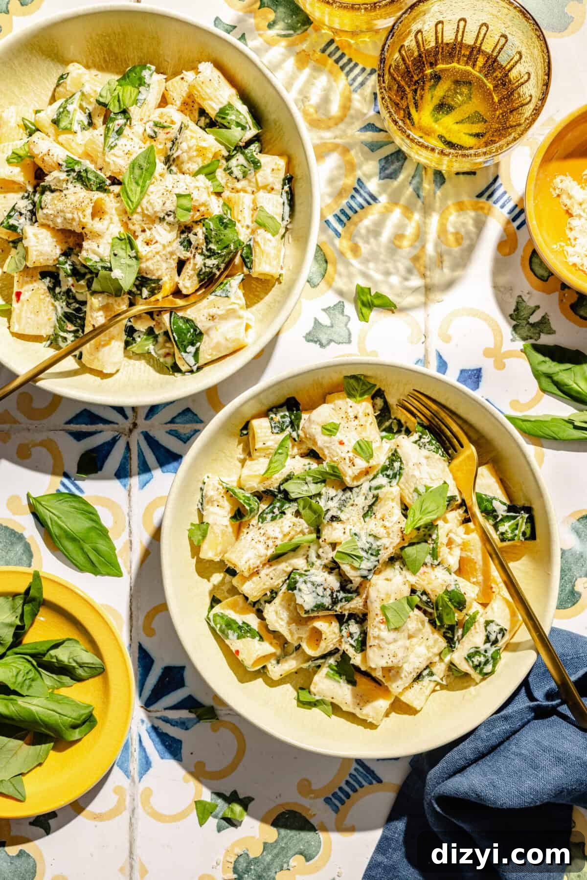 Creamy Lemon Pasta with Ricotta and Basil in two shallow bowls on tiled surface with glasses, and other small plates around it.