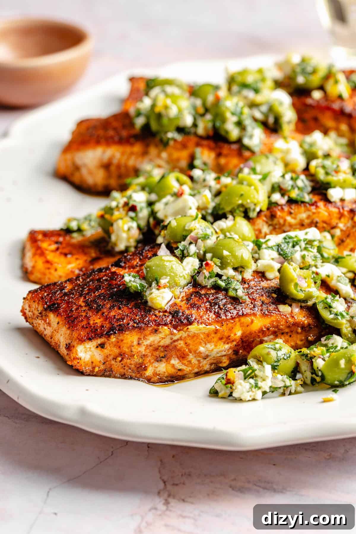 Close up of Pan-Seared Salmon with Castelvetrano Olive and Feta Salsa on platter.