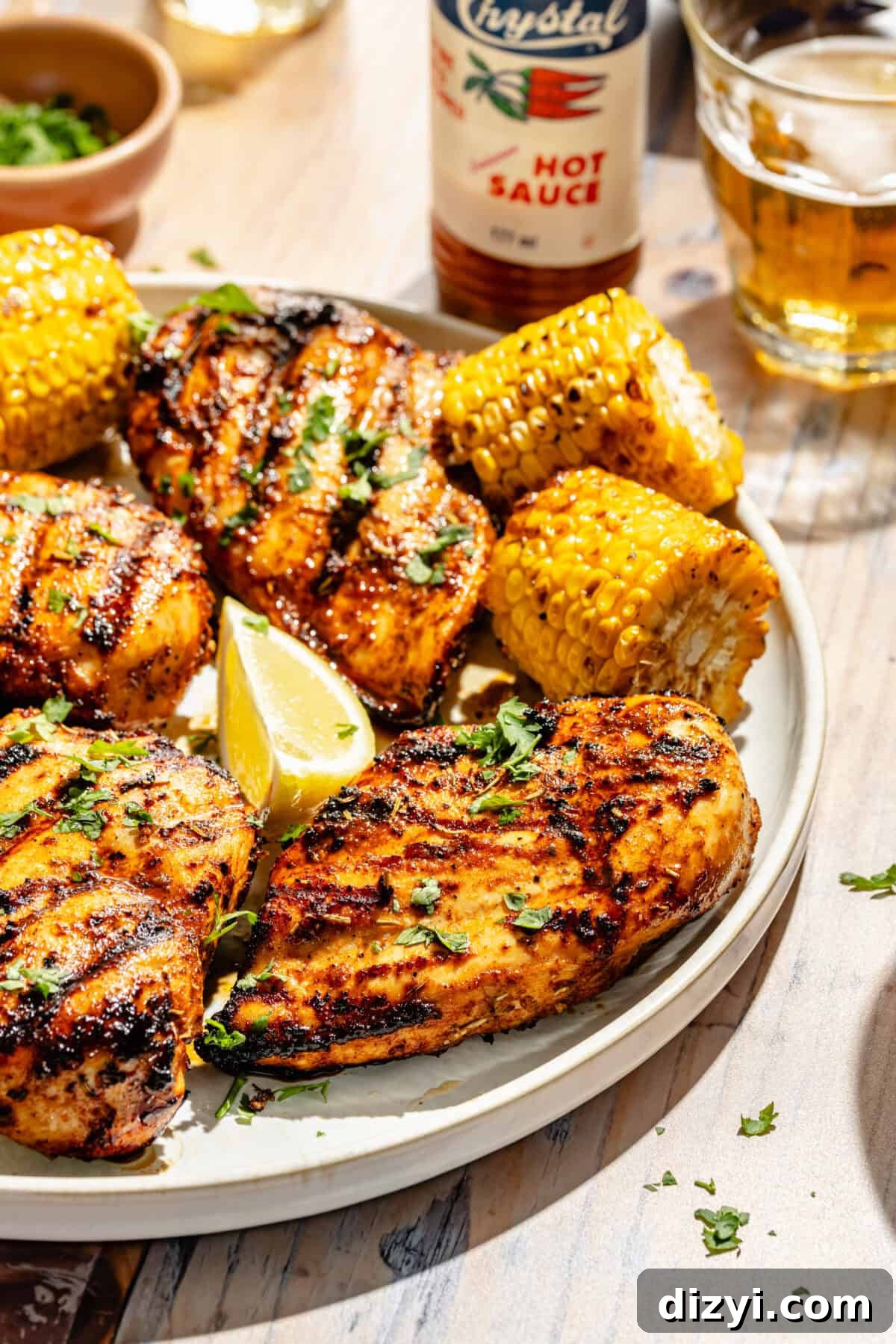 Smoky Grilled Cajun Chicken Recipe 3 Grilled Cajun Chicken on plate with corn and sliced lemons.