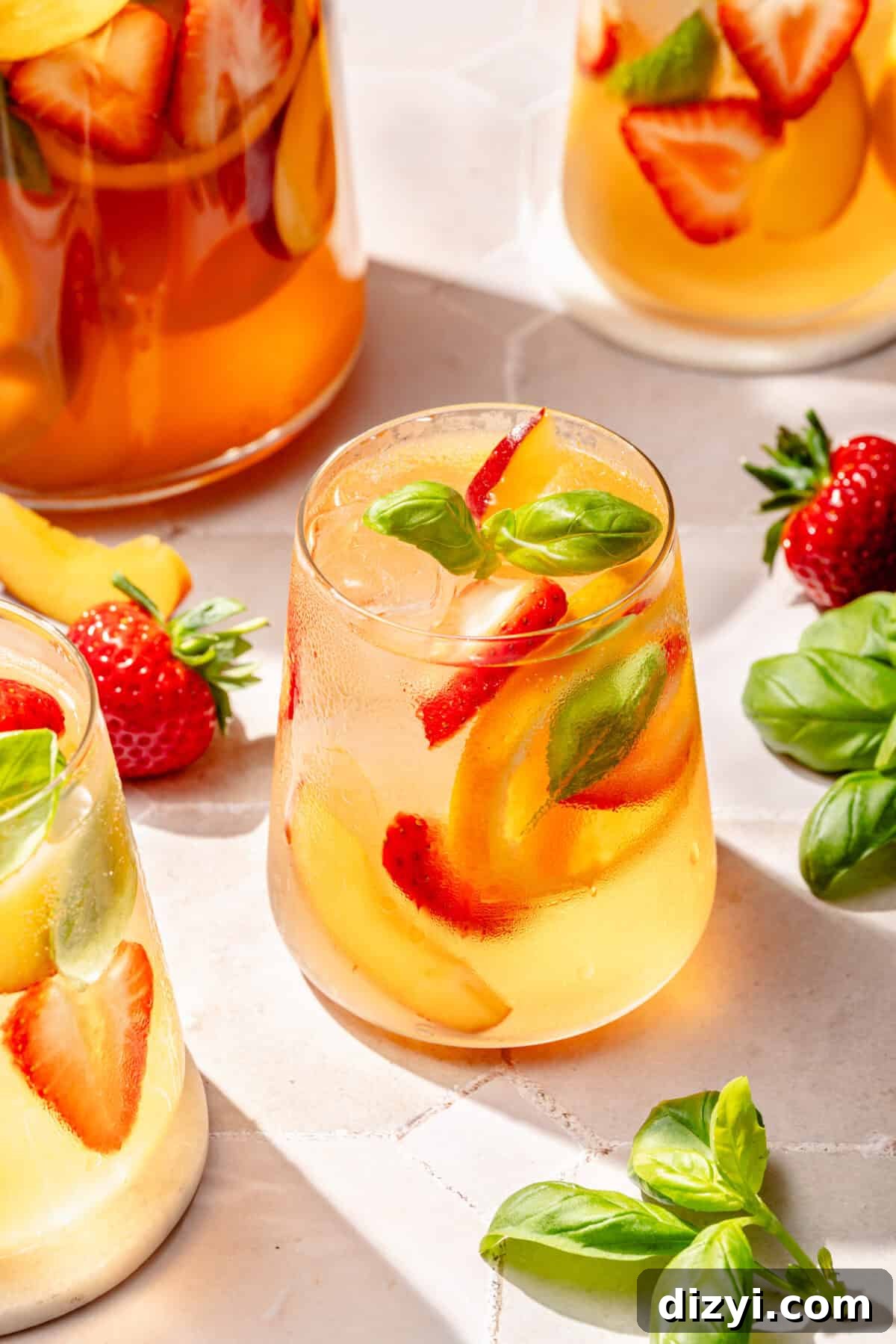 Refreshing Rosé Sangria for Summer Gatherings 2 Summer Rosé Sangria in glass with a pitcher behind it.