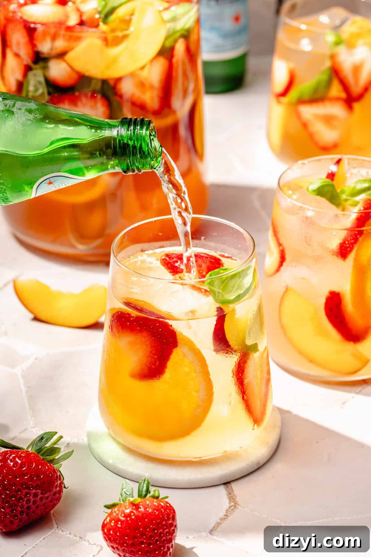 Refreshing Rosé Sangria for Summer Gatherings 4 Summer Rosé Sangria in glass with sparkling water pouring in.