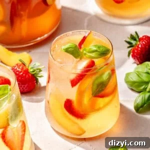 Refreshing Rosé Sangria for Summer Gatherings 5 Summer Rosé Sangria in glass with a pitcher behind it.