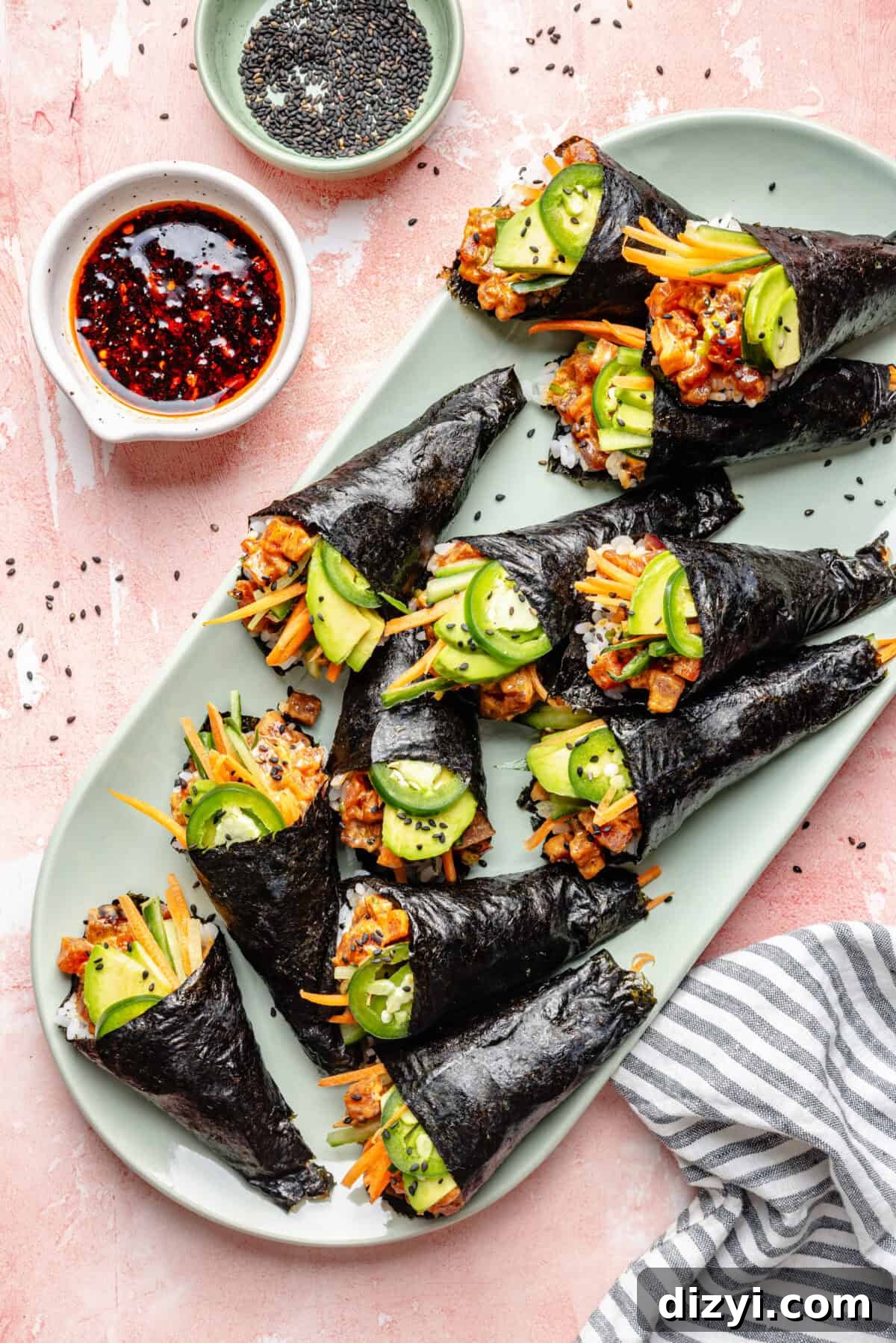How to Make Spicy Tuna Hand Rolls 2 Spicy Tuna Hand Rolls on a platter with small dipping sauce bowl on side.