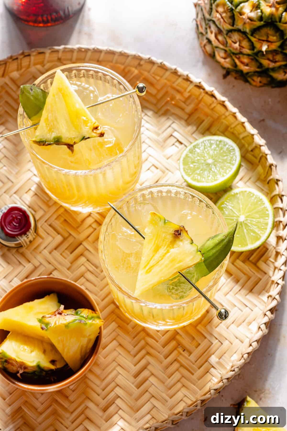 Kauai Margarita: Smoky Pineapple Cocktail Recipe 3 The Kauai Margarita in two glasses on woven tray.