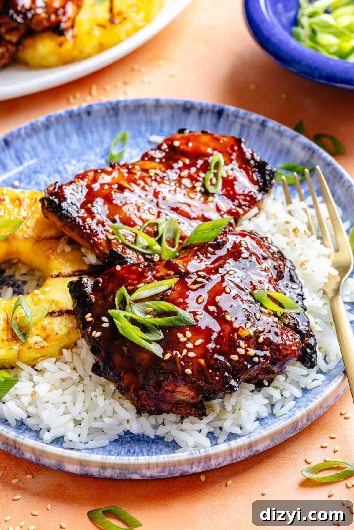 Huli Huli–Inspired Chicken in bowl over rice with sliced pineapple.