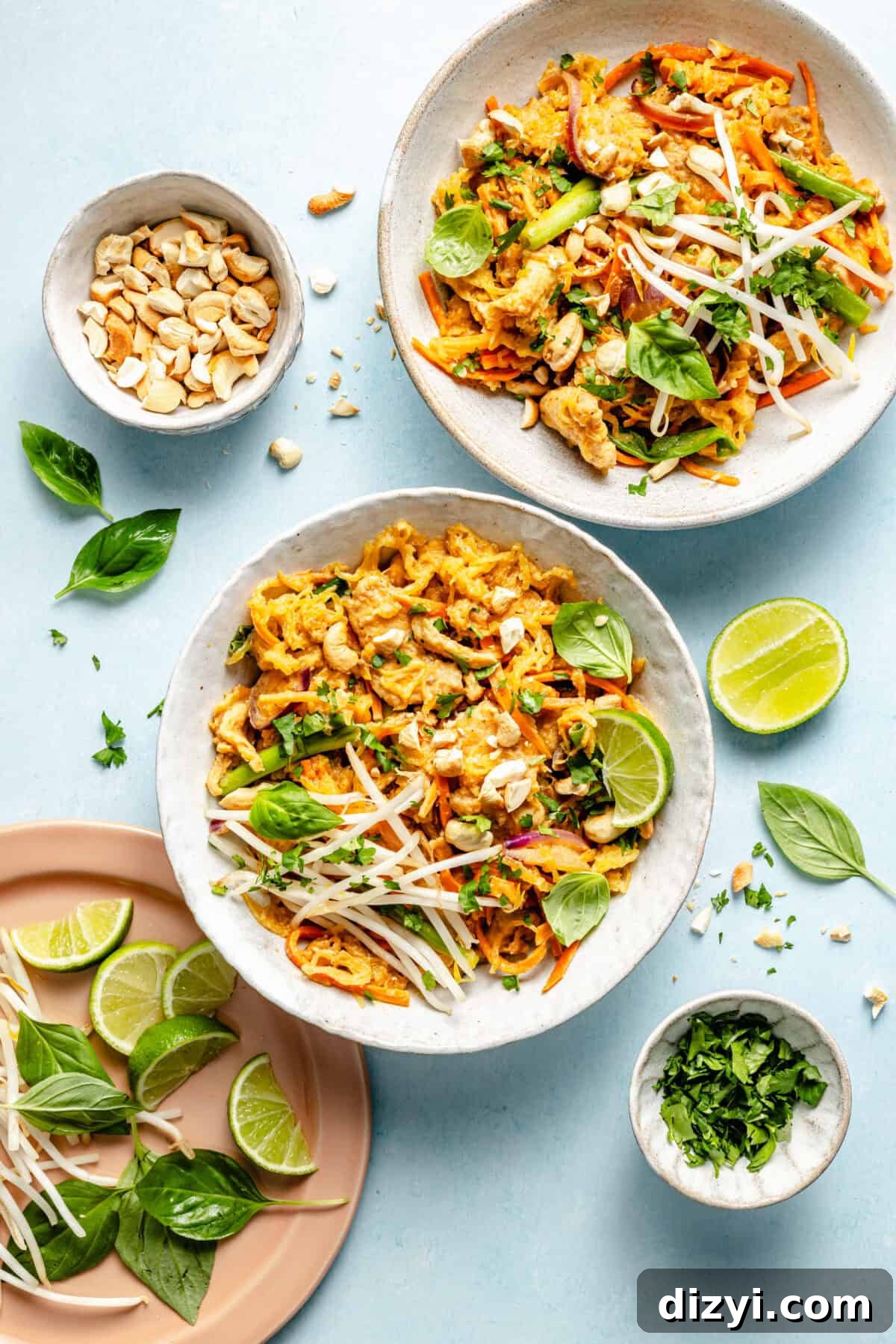 Whole30 Spaghetti Squash Pad Thai Recipe 2 two white bowls filled with spaghetti squash pad thai on a light blue background; a garnish of lime juice, fresh basil, and bean sprouts