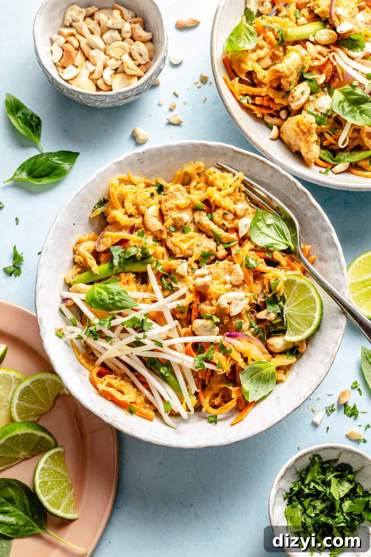 Whole30 Spaghetti Squash Pad Thai Recipe 5 a large white bowl with spaghetti squash pad thai garnished with lime wedges, fresh herbs, and bean sprouts