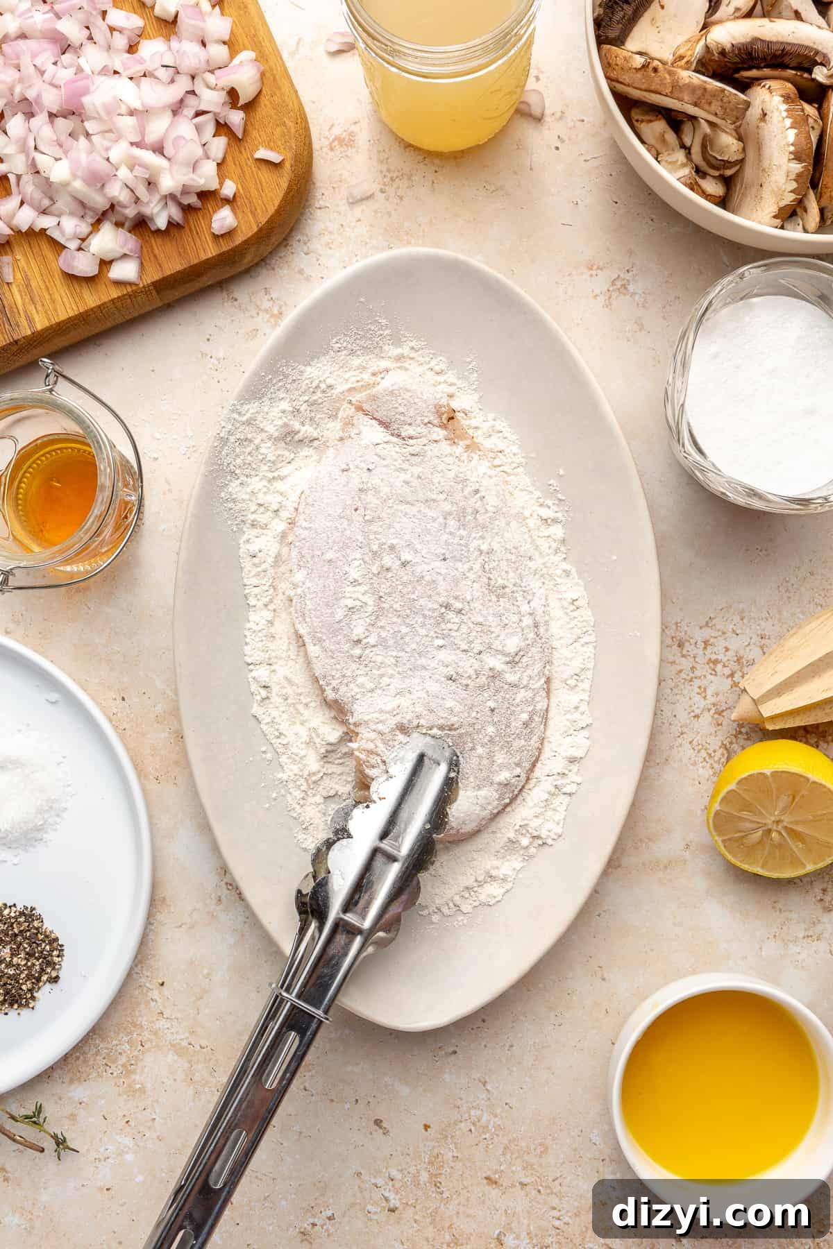 Chicken breast on plate with cassava flour. Tongs being used to grab chicken.