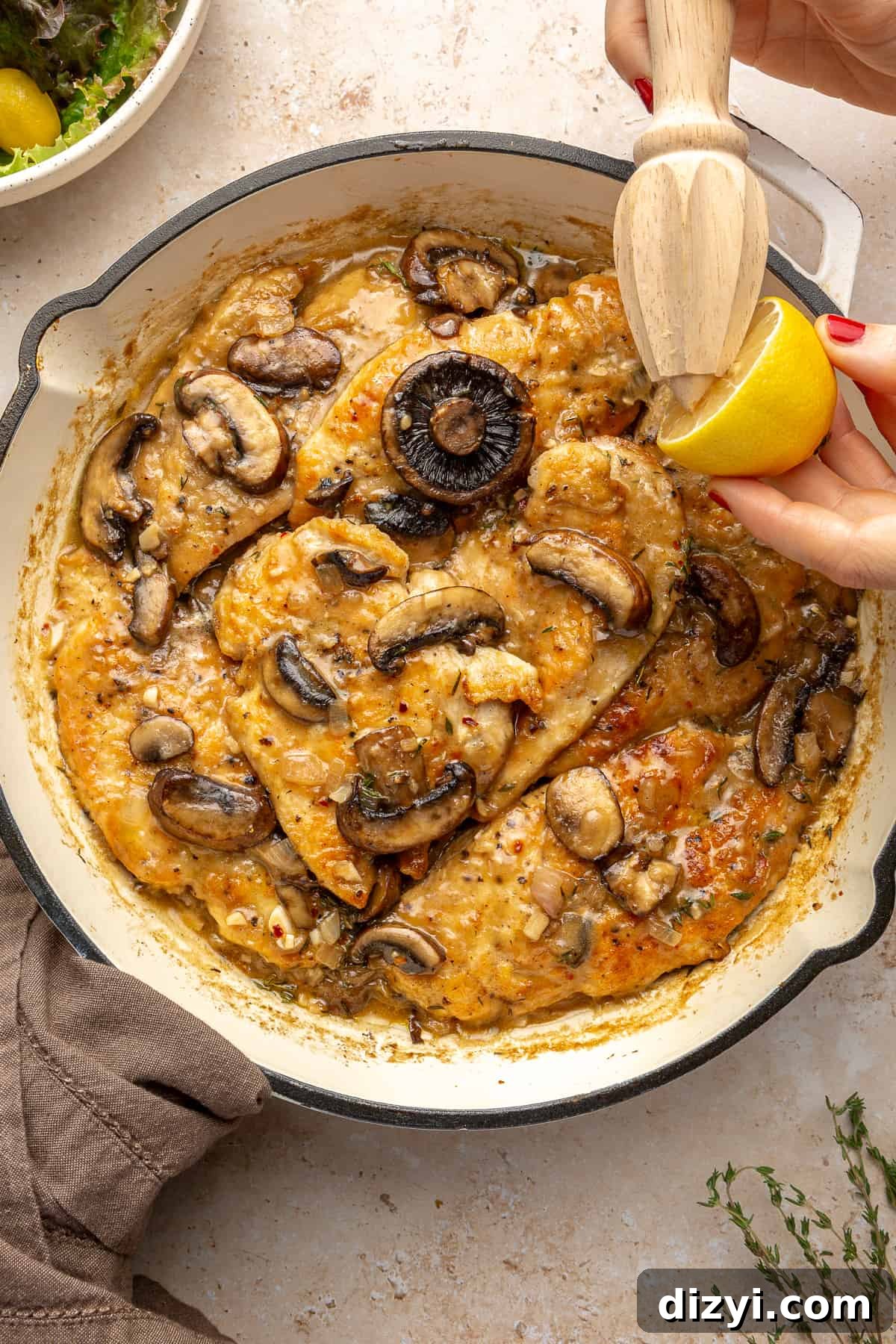 Whole30 Chicken Marsala in skillet with lemon being squeezed over it.