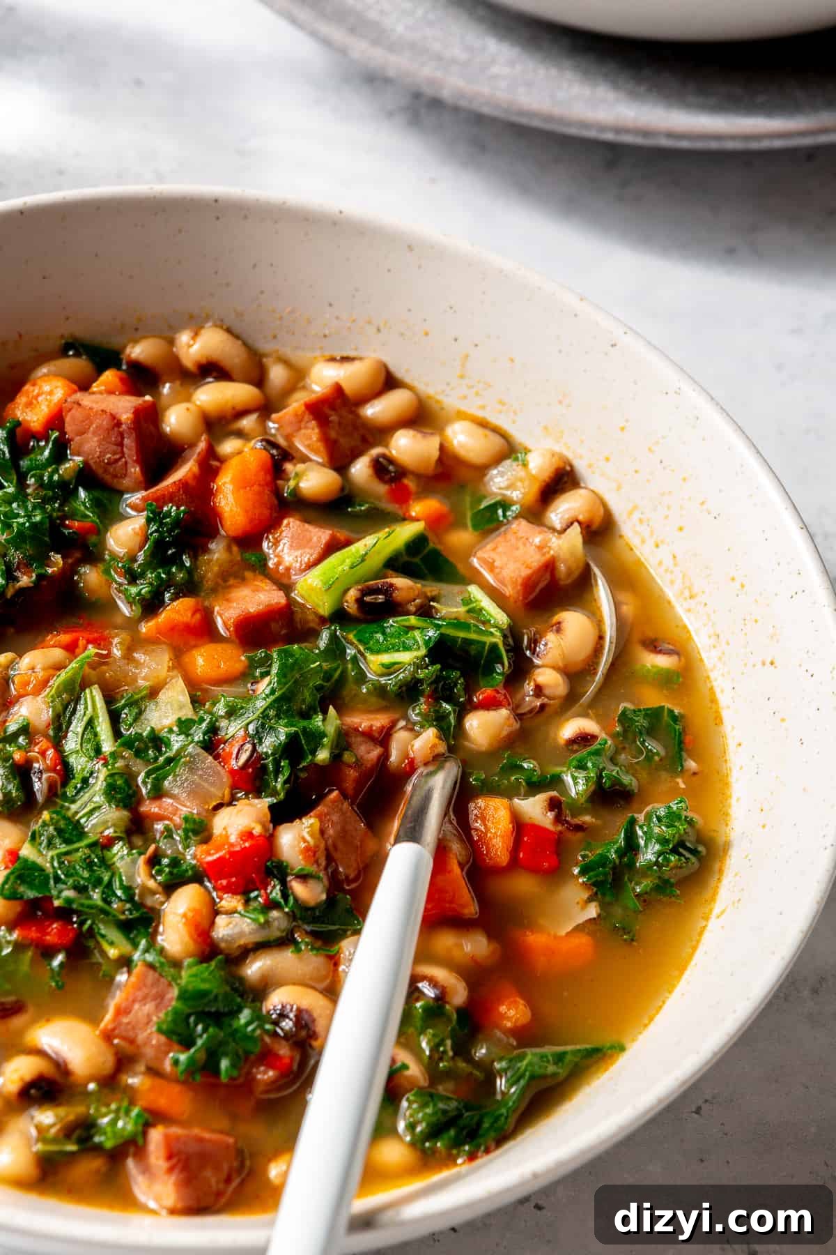 Close-up of Black-Eyed Pea Soup in bowl with spoon tucked into it.