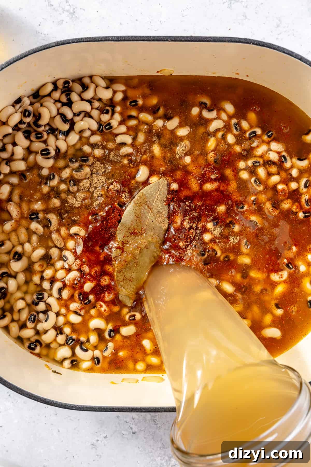 Broth pouring into soup base in dutch oven.