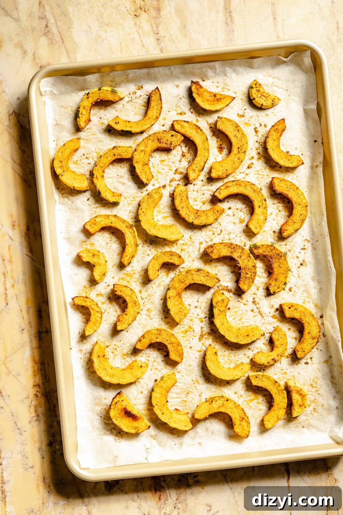 The thinly sliced delicata squash for the Kale Salad with Roasted Delicata Squash and Miso Dressing on a baking tray.