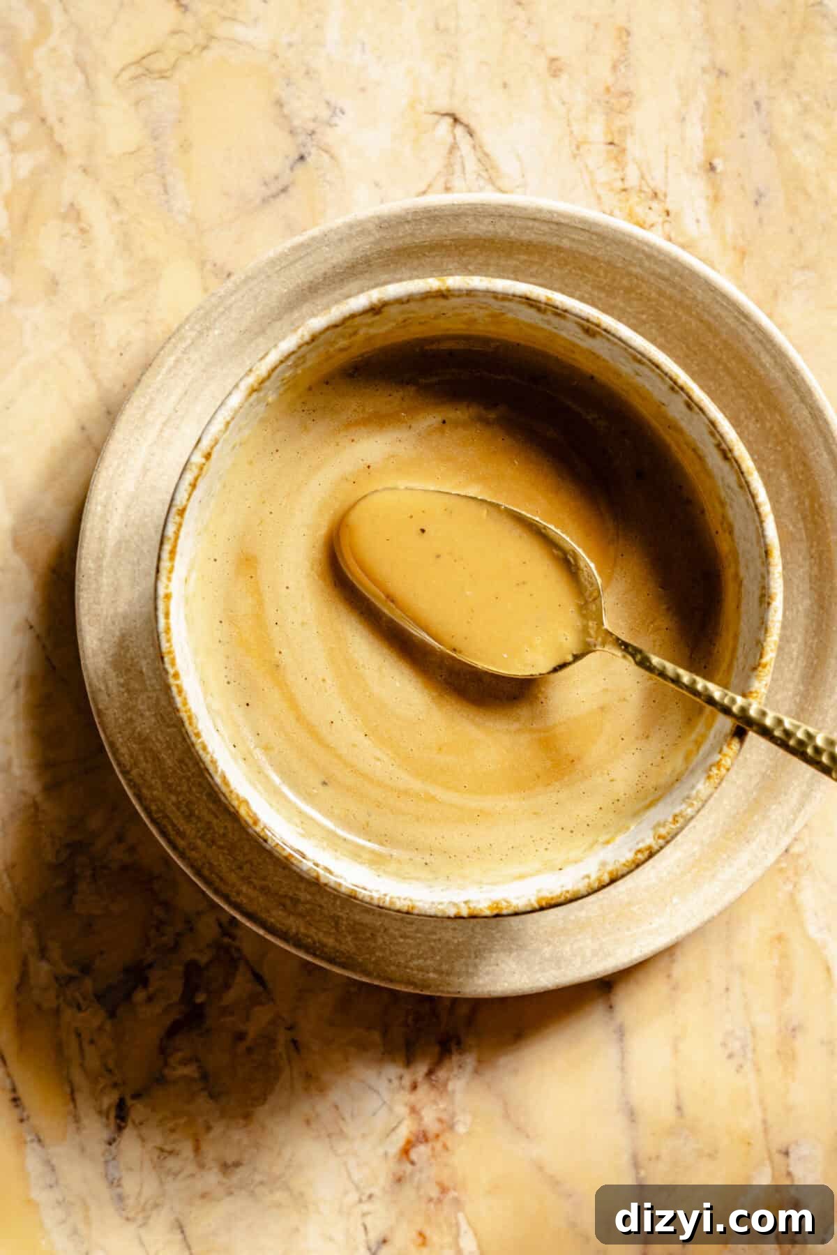 The miso-dressing for the Kale Salad with Roasted Delicata Squash and Miso Dressing in a tan bowl with a silver spoon.