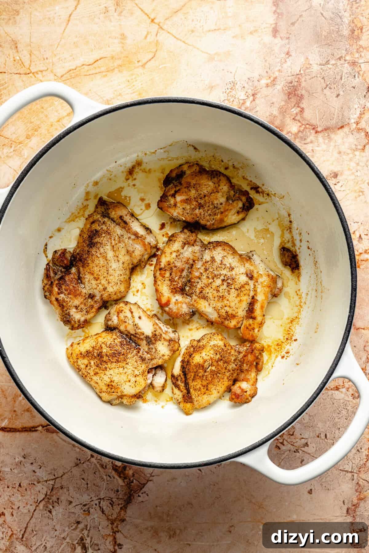 seasoned and seared chicken thighs in a large white pot
