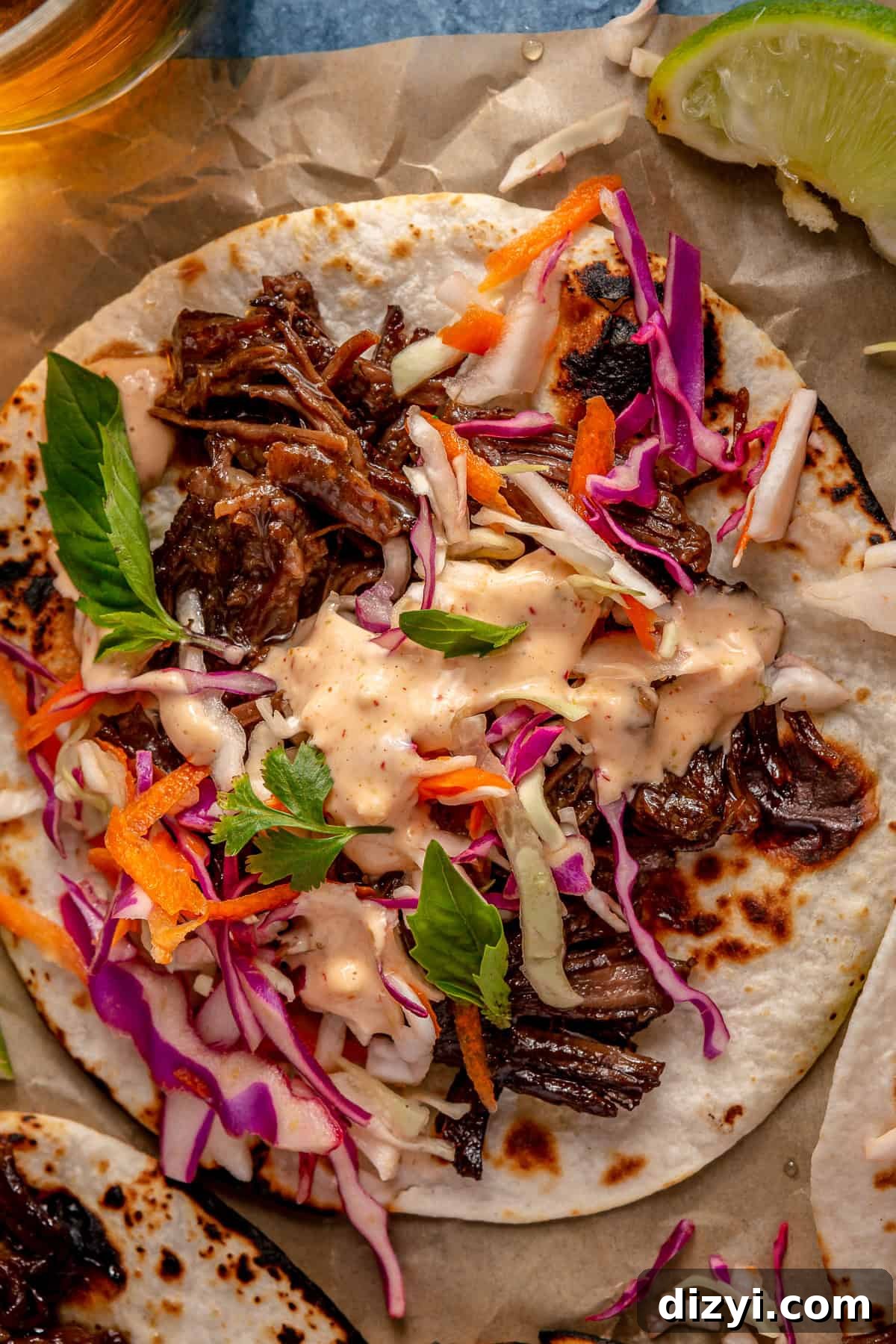 A close-up shot of a Five Spice Short Rib Taco with the sriracha aioli and slaw on top.