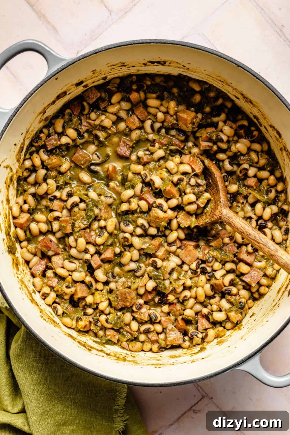 Classic Hoppin' John: Southern Black-Eyed Peas Recipe 4 The Hoppin' Johns cooking in a large dutch oven with a wooden spoon. A green napkin is also visible in the image.