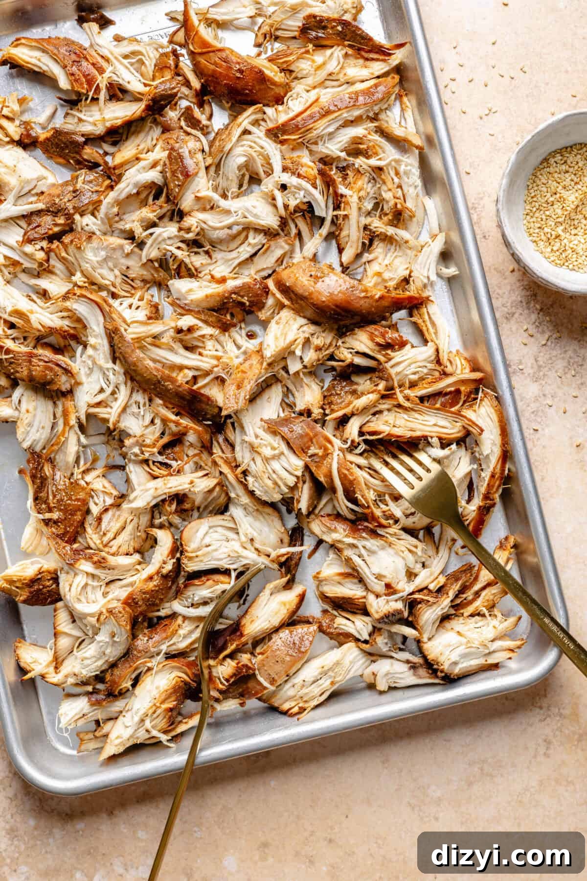 Cooked Slow Cooker Honey-Sesame Chicken shredded on sheet pan.