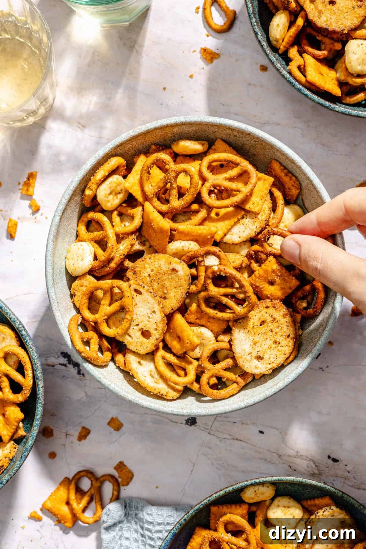 Cajun Cheddar Snack Mix with hand grabbing out of bowl.